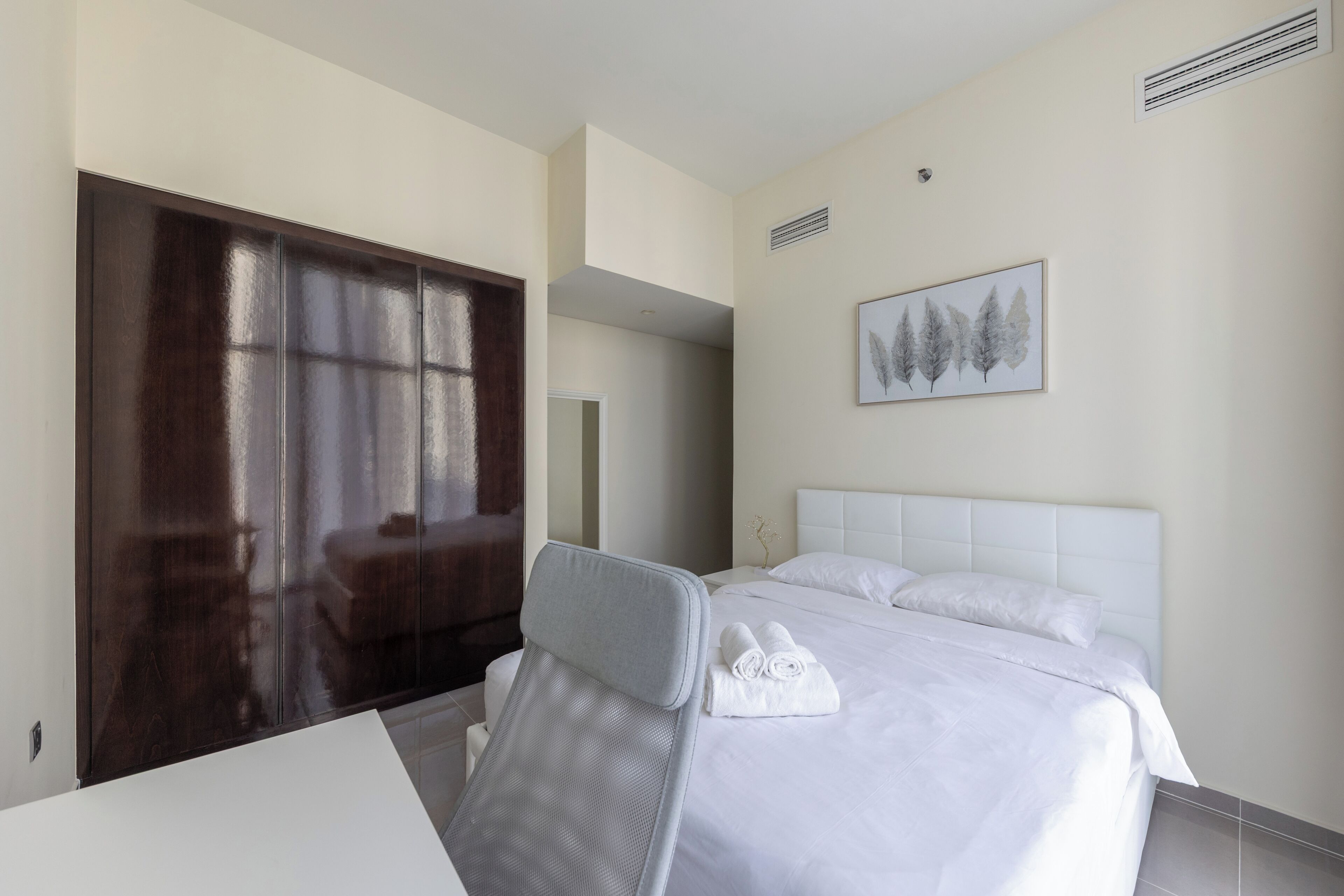 A hotel room with a bed, a chair, a desk, and a wardrobe.