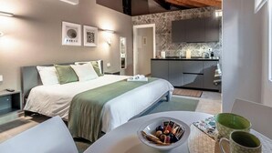 Une chambre d’hôtel moderne équipée d’un lit, d’une table de chevet et d’une petite table sur laquelle se trouvent un bol et des tasses.