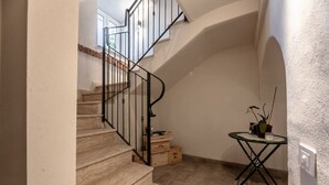 Un escalier avec une rampe noire, des marches en bois et une petite table sur laquelle est posée une plante.