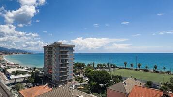 Un hôtel situé sur la côte, avec vue sur la mer, un immeuble imposant et un champ verdoyant.