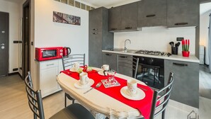 A modern kitchen with dark cabinets, a red countertop, and a dining table set with white cups and a red table runner. - [Sea View Penthouse] Free Park • A/C • Hiper Wifi (Savona)