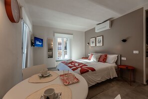 A hotel room with a bed, a TV, a dining table with a cup and saucer, and a window. - [Alta Via 1] Free Parking • Sea 20 min • A/C (Altare)