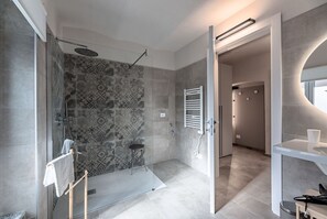 Un baño moderno con ducha, baldosas estampadas, puerta de cristal y un perchero para toallas.