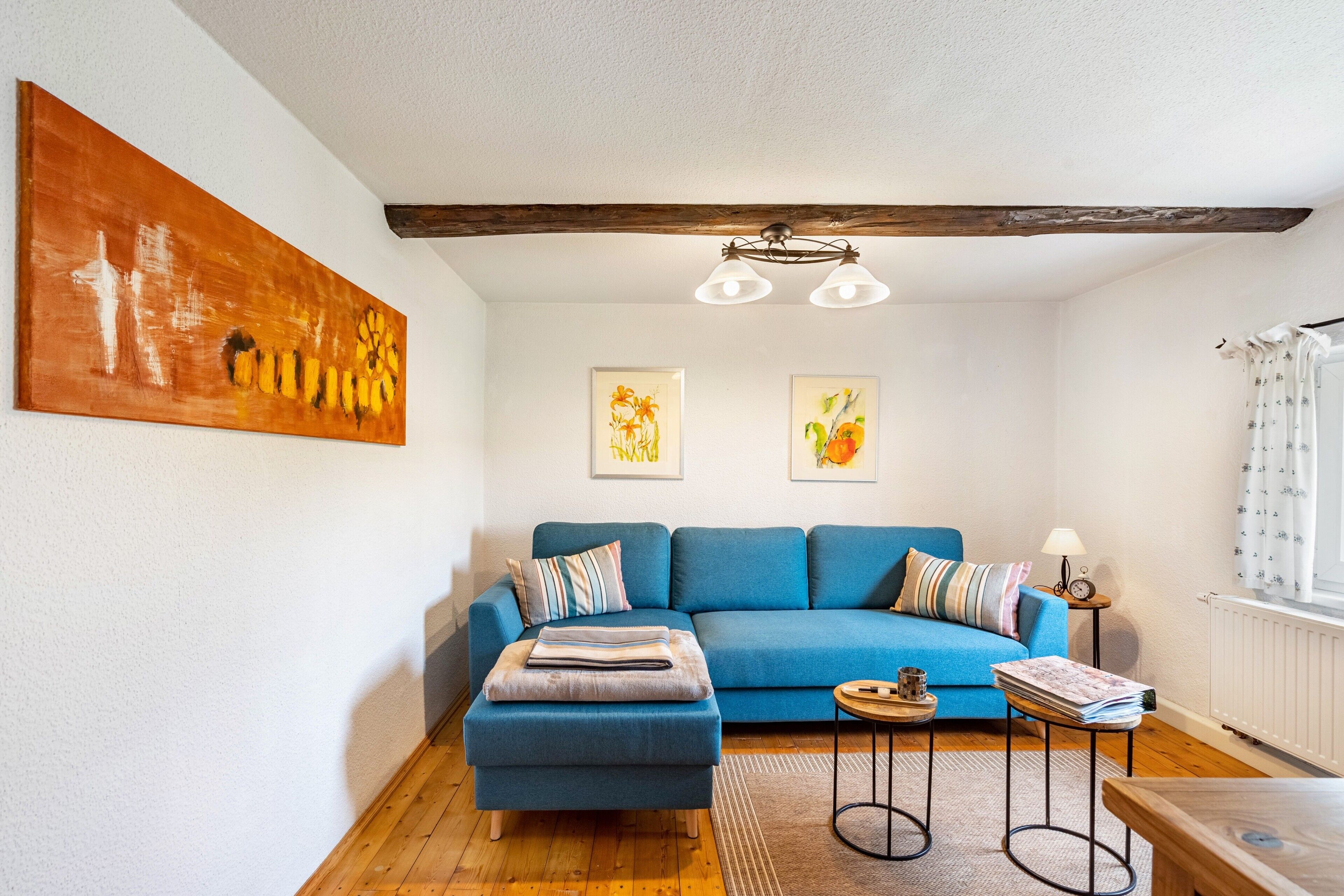 Un salon avec un canapé bleu, une table basse en bois et un tableau accroché au mur.