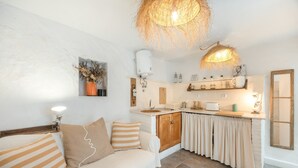Ett mysigt vardagsrum med en soffa, ett kök med en diskho och en hängande lampa.