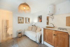 A modern kitchen with wooden cabinets, a sink, and a hanging light fixture. - Central Apartment in Vejer, Perfect for Couples! (Vejer de la Frontera)