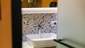 Un baño con un lavamanos blanco, un espejo y una pared con estampado de terrazo.