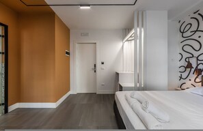Ein Hotelzimmer mit Bett, einem Badezimmer mit Spiegel und einer Tür zu einem anderen Raum.