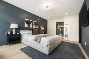 A modern bedroom with a bed, bedside tables, and artwork on the wall. - Rooftop Sauna + Hot Tub | Spa Room | Cabana! (Pittsburgh)