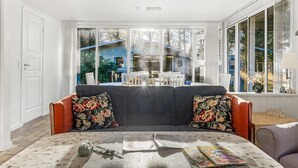Una sala de estar con sofá, mesa de centro y ventanas amplias.