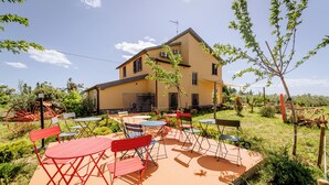 A yellow house with a patio area featuring red and blue outdoor furniture.