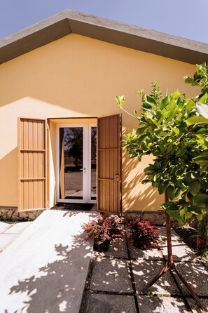 A building with a door, wooden shutters, and a small tree. - Podere 109-BioWine: Exclusive Villa with Hot Tub in the Tuscan Maremma (Toscana)