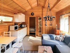 A cozy cabin interior with a dining area, kitchenette, and a sofa with cushions. - 4 Person Holiday Home in Yngsjo (Yngsjo)