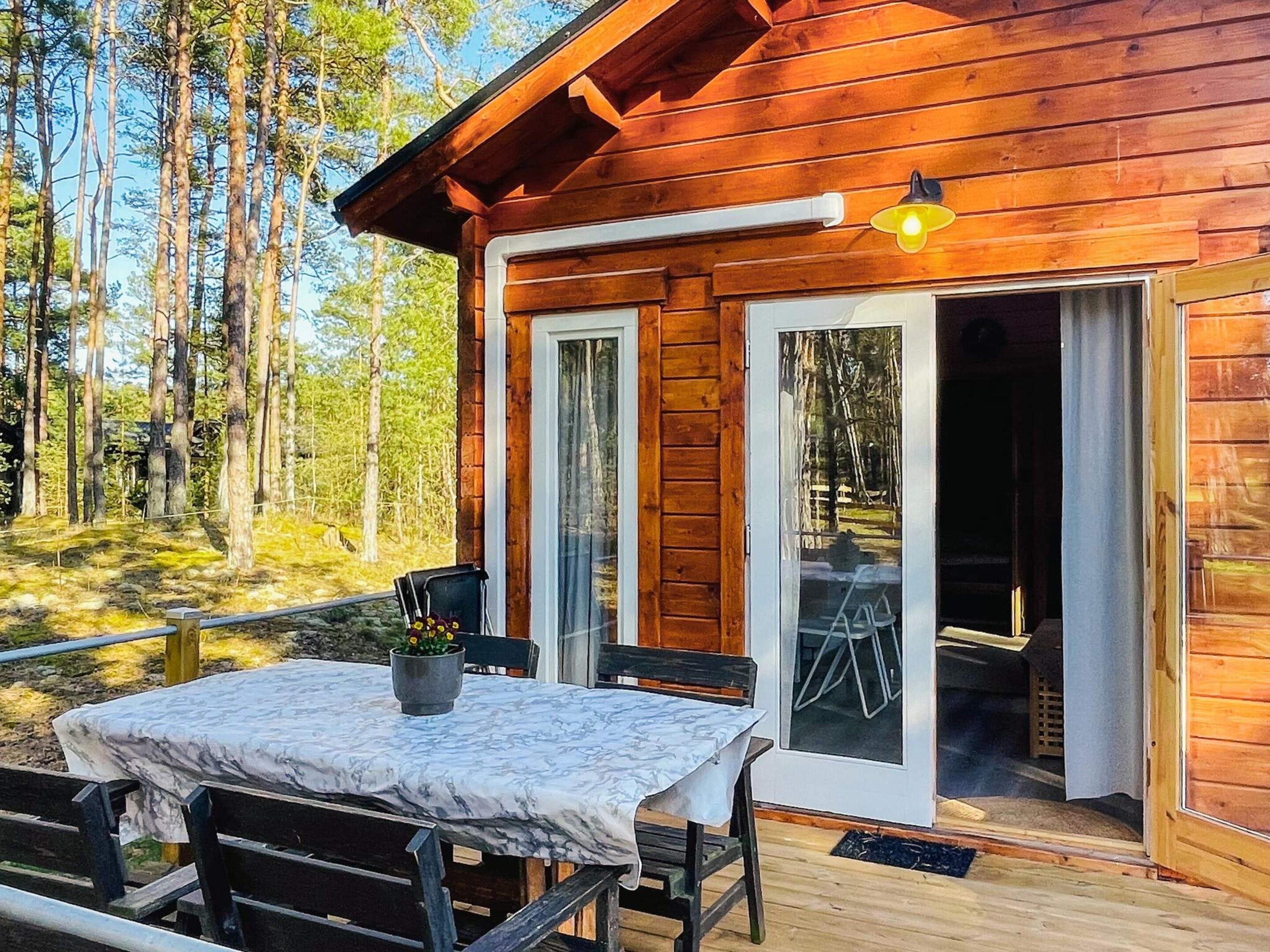 A wooden cabin with a patio table and chairs, a potted plant, and a sliding glass door leading to an interior space.