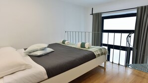 A modern bedroom with a bed, pillows, a window with curtains, and a balcony. - 4BNB - Loft Colosseum 3 (Rome)
