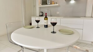 A modern kitchen with a white table, two wine glasses, a wine bottle, and a microwave on the countertop. - 4BNB - Loft Colosseum 3 (Rome)