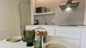 A modern kitchen with a microwave, toaster, and stainless steel range hood. - 4BNB - Loft Colosseum 3 (Rome)