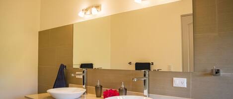 A modern bathroom with two sinks, a large mirror, and wall-mounted lights.