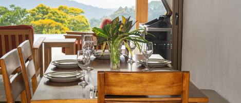 A dining table set with plates, glasses, and a plant, with chairs around it.