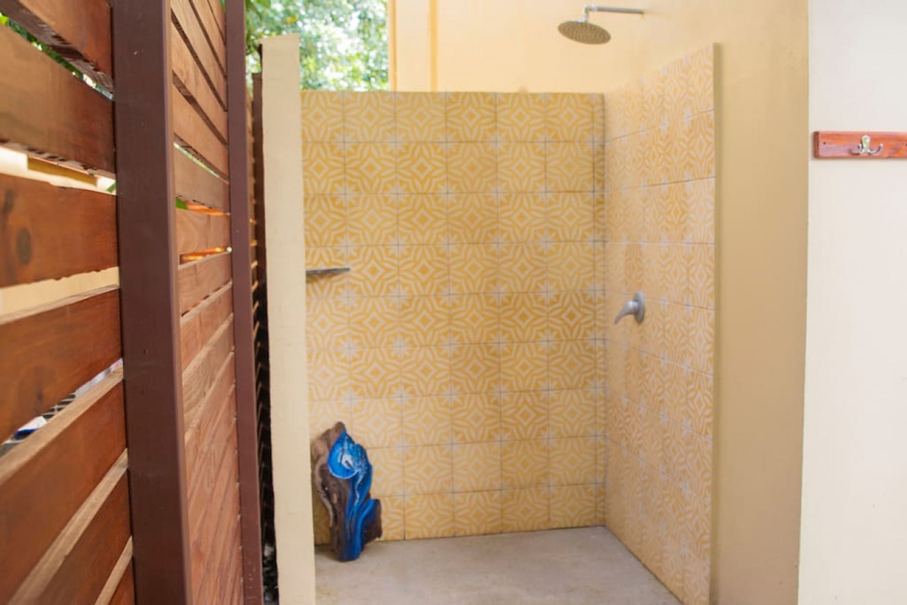 A bathroom with patterned yellow tiles, a shower, and a wooden door.