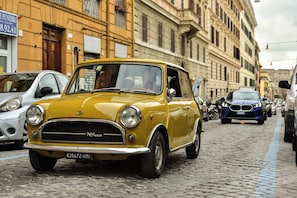 Ein gelber Oldtimer auf einer Kopfsteinpflasterstraße geparkt.