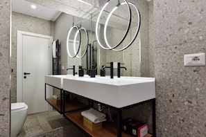 A modern bathroom with a double sink, two mirrors, a towel rack, and a toilet. - 4BNB - Loft Colosseum 1 (Rome)
