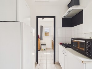 Una cocina con armarios blancos, un microondas negro y una ventana con vistas.