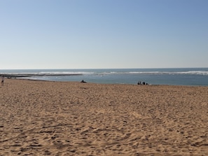 Platja ampla i sorrenca amb onades al fons.