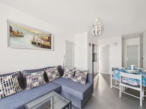 A modern living room with a sofa, coffee table, and a dining area with a table set for two.