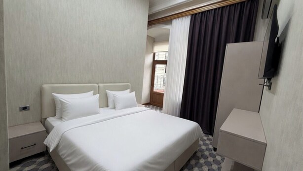Habitación de hotel con cama, armario, mesita de noche y vistas al exterior.
