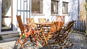 Ein Essbereich im Freien mit Tisch und Stühlen, einem Fenster und einem Zaun.