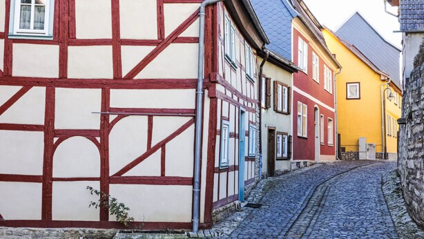 Eine enge Kopfsteinpflasterstraße gesäumt von traditionellen Fachwerkhäusern.