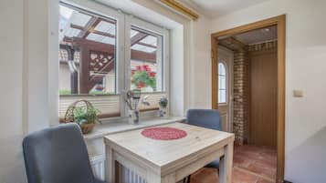 Ein Essbereich mit Tisch und Stühlen, ein Fenster mit Aussicht und eine Tür zu einem weiteren Raum.