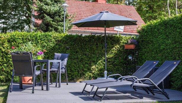 An outdoor patio with a table and chairs, a lounge chair, and a potted plant. - Apartment “Max” with Private Terrace, Garden, and Wi-Fi (Heringsdorf)