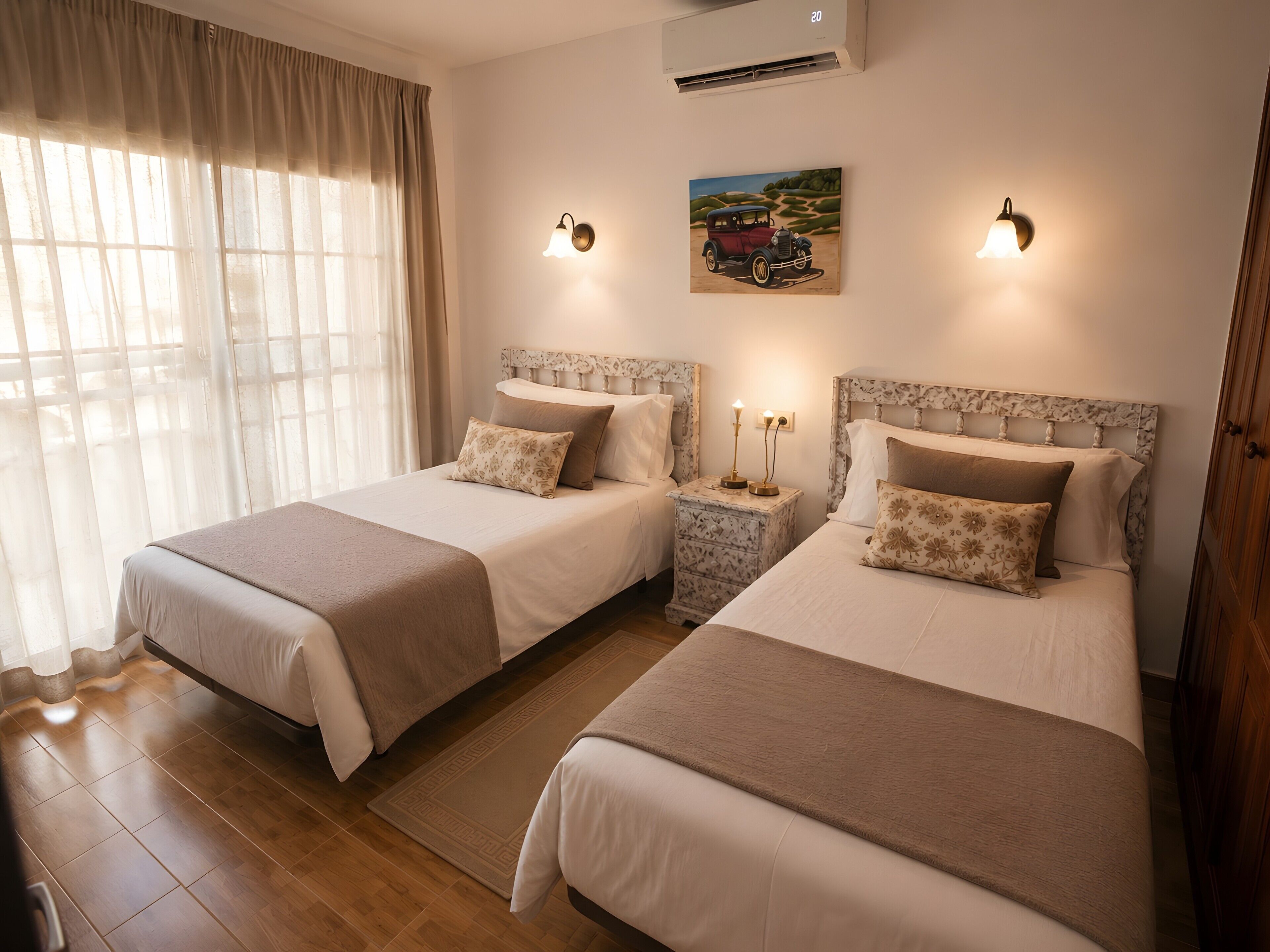 A hotel room with two beds, a painting on the wall, and an air conditioning unit.