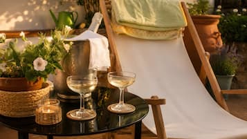 Een tafel met een kaars, een glas witte wijn en een bloempot.