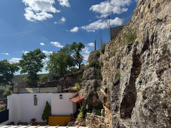 Un bâtiment à la façade blanche, au toit recouvert de tuiles rouges et doté d’un mur en pierre.