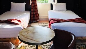 A room with two beds, a round table, and a chair.