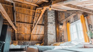 Ein rustikaler Raum mit sichtbaren Holzbalken, einer Steinwand und einem Bett mit Holz Kopfteil.
