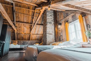 Una habitación rústica con vigas de madera a la vista, una pared de piedra y una cama con cabecero de madera.