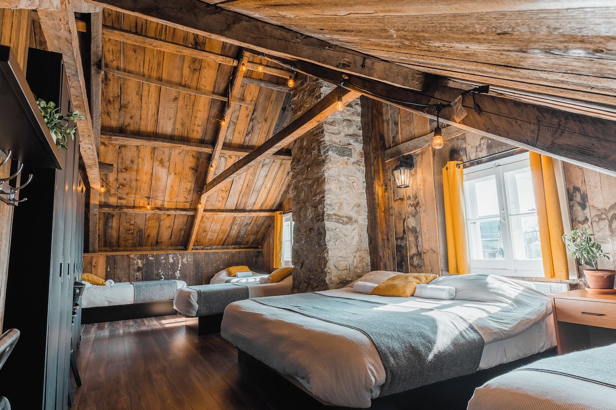 Een rustieke kamer met houten balken, een stenen muur en een bed met een plant.