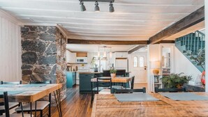 Eine geräumige Küche mit Steinwand, Holzboden und einer Essecke mit Tisch und Stühlen.