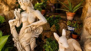 Een beeld van een vrouw in een tuin met potplanten en een konijn.