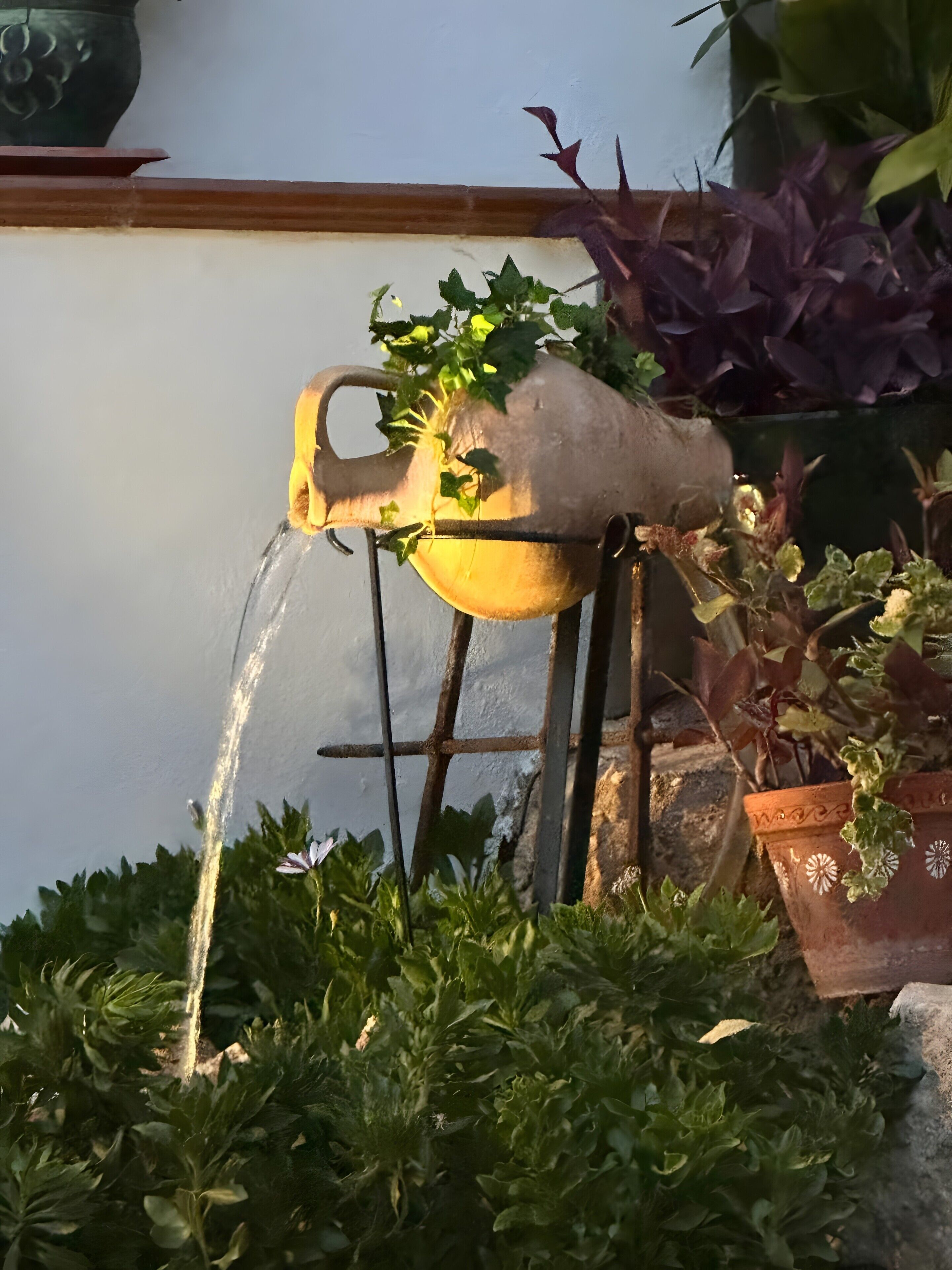 A water feature with a spout and a plant growing out of it.
