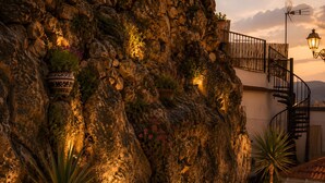 Une falaise rocheuse ornée de plantes en pot, un escalier en colimaçon et un lampadaire.