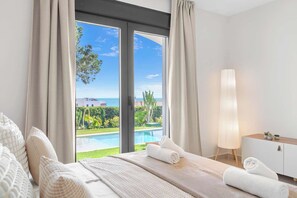 A bedroom with a large window, a bed, a bedside table, and a lamp. - Stunning villa Dolce vita - ref 69 (Las Lagunas de Mijas)