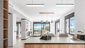 A modern kitchen with a central island, large windows, and a view of the sea. - Stunning villa Dolce vita - ref 69 (Las Lagunas de Mijas)