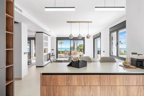 A modern kitchen with a central island, large windows, and a view of the sea. - Stunning villa Dolce vita - ref 69 (Las Lagunas de Mijas)