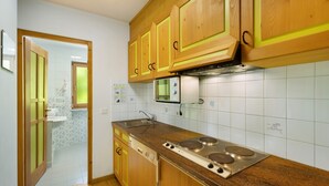 A kitchen with wooden cabinets, a stainless steel stove, and a tiled backsplash. - Apartment '8 Residence Ciasa Ulli Typ B' with Mountain View, Shared Terrace and Wi-Fi (San Cassiano)