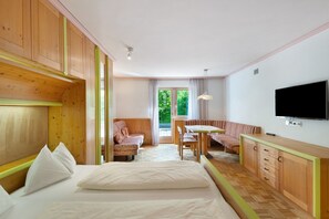 A room with a bed, a sofa, a dining table, and a TV.
